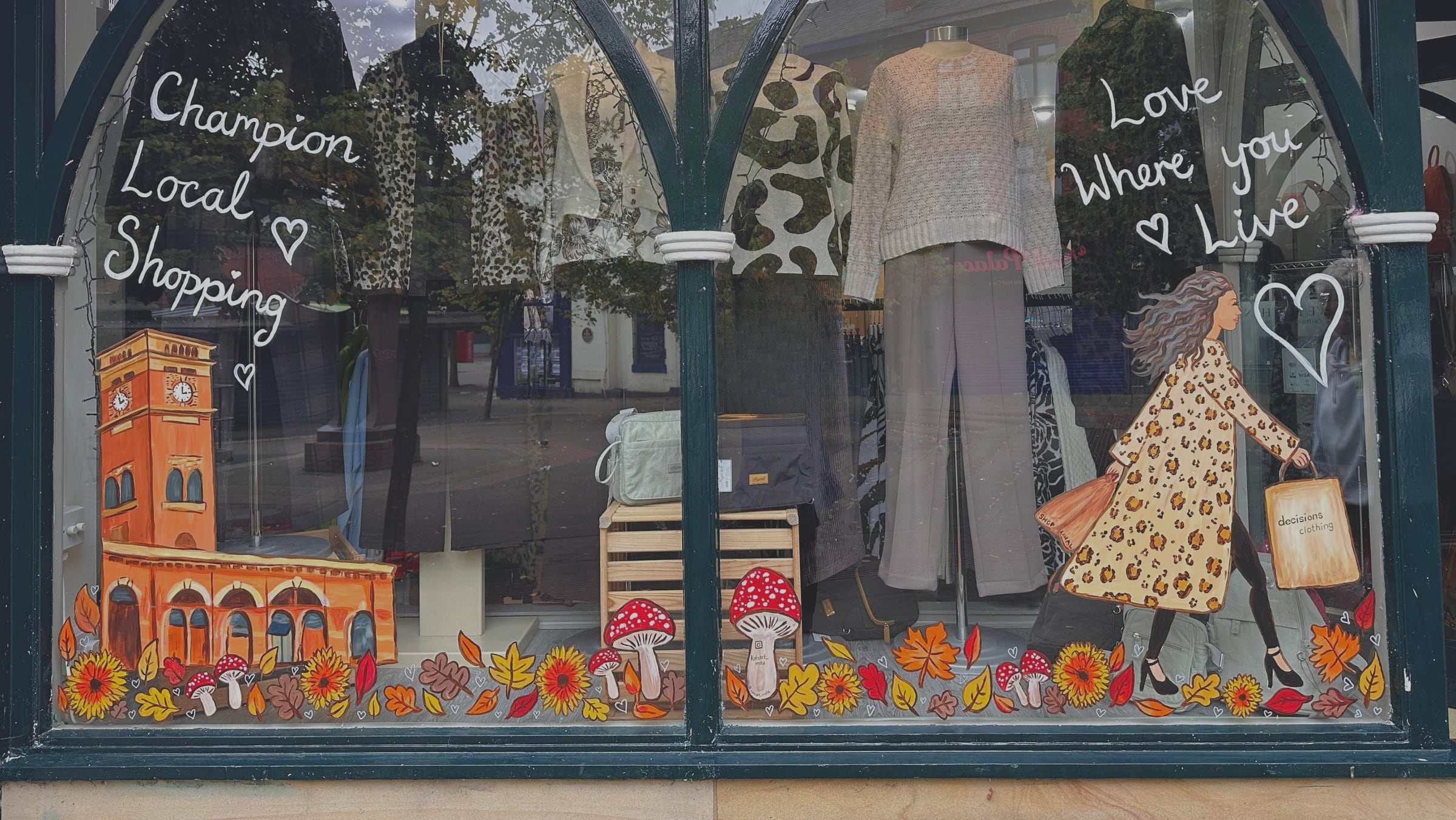 The autumn window display at Decisions Clothing, decorated with local landmarks, flowers and fashion illustrations